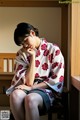 A woman in a kimono sitting on a bench.