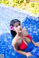 A woman in a red bikini sitting in a pool.