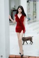 A woman in a red dress standing next to a dog.