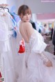 A woman in a wedding dress standing in front of a rack of dresses.