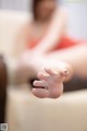 A woman sitting on a couch with her hand outstretched.