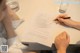 A woman sitting at a table writing on a piece of paper.