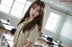 A woman standing in front of a classroom full of desks.