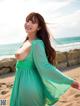 A woman in a green dress standing on a beach.