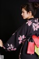 A woman wearing a black kimono with pink flowers on it.