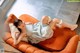 A woman laying on top of an orange couch.