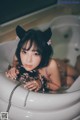 A woman in a bathtub with a cat ears on her head.