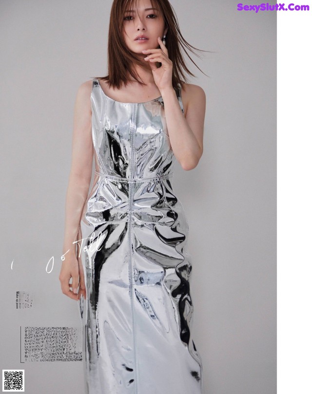 A woman in a silver dress talking on a cell phone.