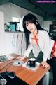 A woman sitting at a desk with a cup of coffee.