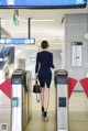 A woman in a blue dress is walking through a train station.