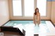 A naked woman standing in a hot tub in a room.