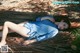 A woman in a blue dress laying on the ground.