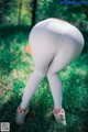 A woman in white leggings is standing in the grass.