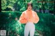 A woman in an orange hoodie standing in the grass.