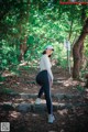 A woman in a white shirt and black leggings standing on some steps.