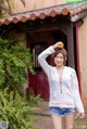 A woman holding an orange in front of a house.