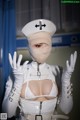 A woman in a white nurse outfit with a bandage on her face.