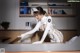 A woman in a white uniform is bending over a desk.