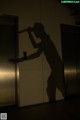 A silhouette of a man holding a baseball bat in an elevator.