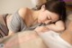 A woman laying in bed with her eyes closed and her head resting on a pillow.