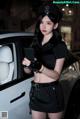 A woman dressed as a police officer standing next to a car.