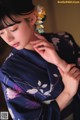 A woman in a blue kimono with a flower in her hair.