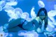 A woman in a bikini laying on a bed surrounded by jellyfish.