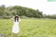 A woman in a white dress and straw hat standing in a field.