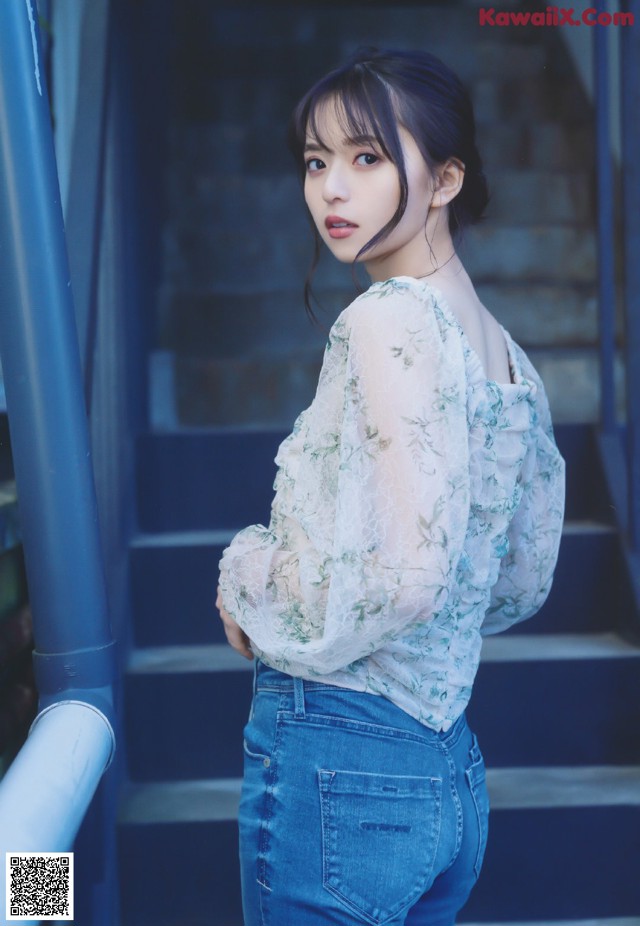 A woman in a white blouse and blue jeans posing for a picture.